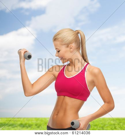 fitness and health concept - young sporty woman with light dumbbells outdoors