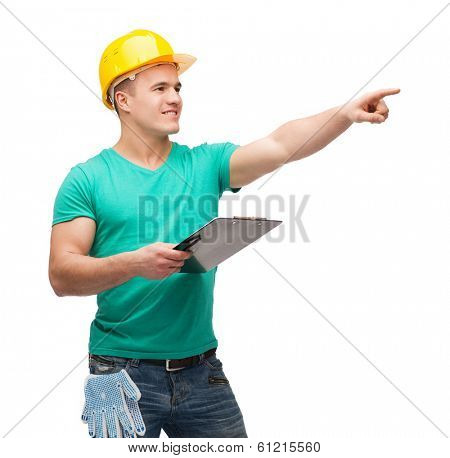 repair, construction and maintenance concept - smiling man in helmet with clipboard pointing finger