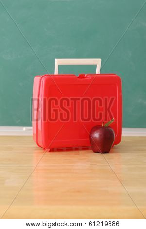 School education still life with apple and luch box, chalkboard background