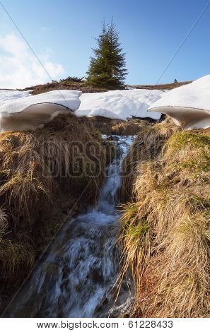 Spring landscape with a creek. Melting snow in the mountains last
