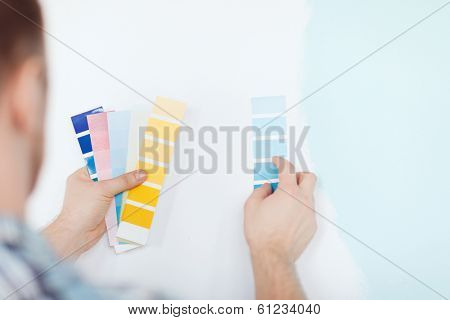 repair, building, technology and home concept - close up of male with color pallets choosing color