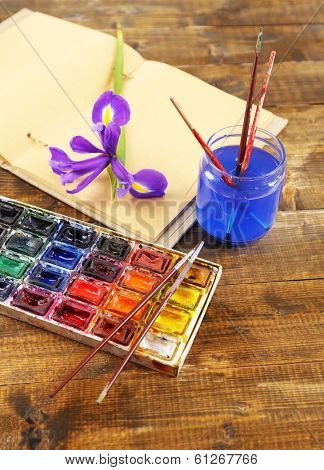 Composition with colorful watercolors, brushes and sketcher on wooden background 