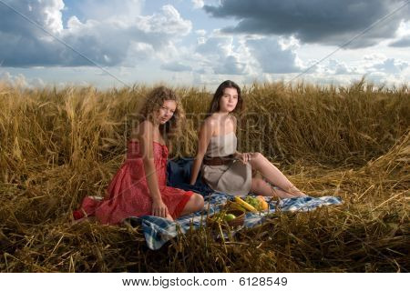 Duas meninas no piquenique no campo de trigo