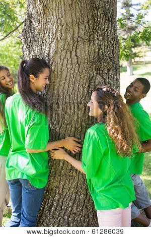 Group of multiethnic environmentalists standing around tree trunk in park
