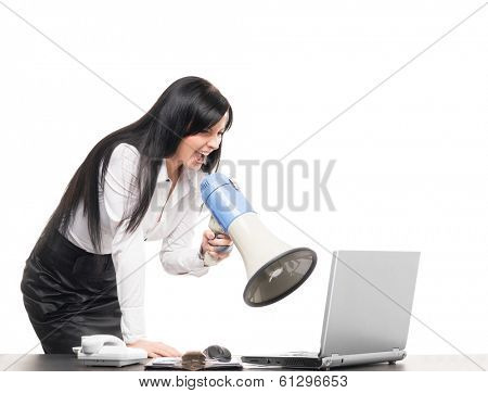 Angry and furious business woman screaming with megaphone at a computer, isolated on white.