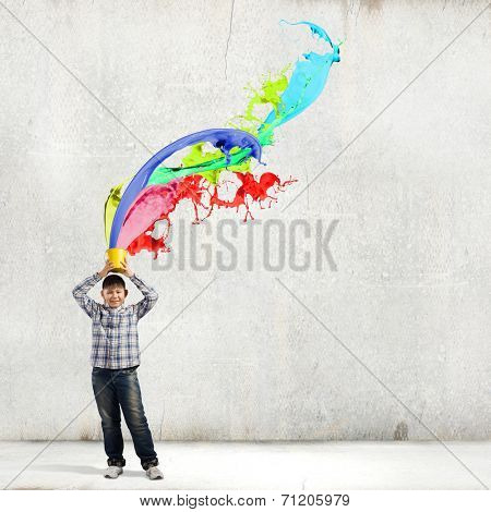 Young boy splashing colorful paint from bucket