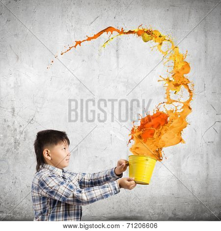 Young boy splashing colorful paint from bucket