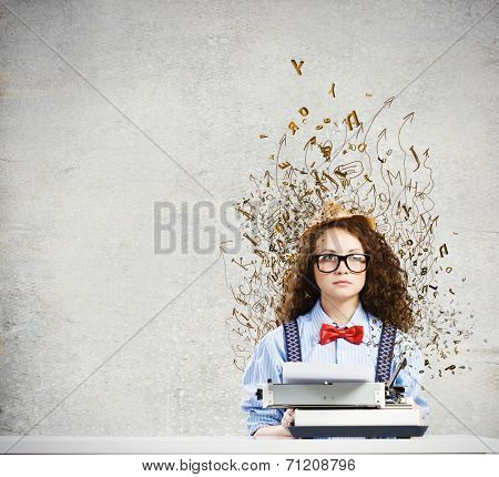 Young funny woman in glasses using typewriter
