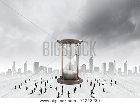 Conceptual image with sandglass and silhouettes of business people around