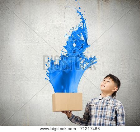 Young boy splashing colorful paint from carton box
