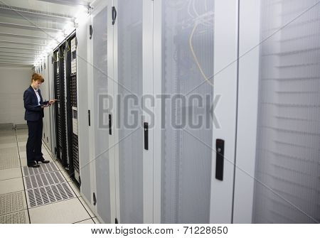 Technician working on servers using tablet pc in large data center
