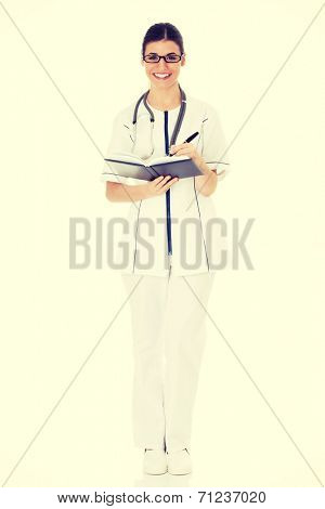 Young female doctor wirting in a book. Isolated on white.
