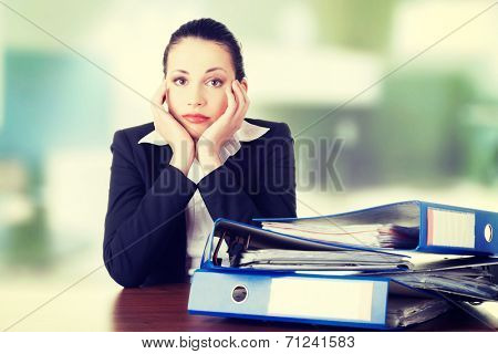 Sad woman with ringbinders sitting at the desk. Tired and exhousted business woman.