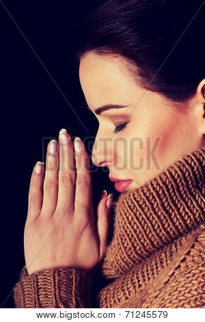 Young woman praying. Over black background.