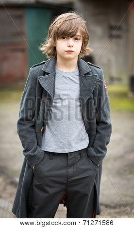 Boy In Long Coat Standing In A Farm Yard