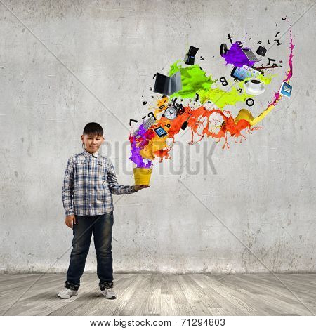 Young boy splashing colorful paint from bucket
