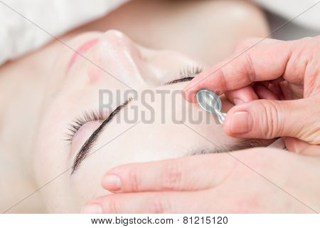 Serum capsule in front of young woman face in spa salon
