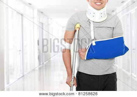 Injured Young Man Use Crutch And Arm Sling
