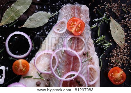 Pangasius fillet with spices and vegetables on firepan background
