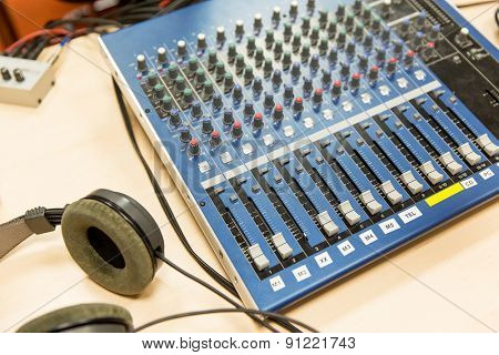 technology, electronics and equipment concept - control panel and headphones at recording studio or radio station