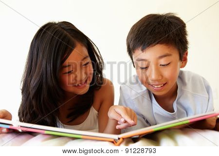 Young Asian girl and boy reading book