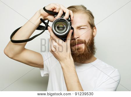 Travel, technology and life style concept: young bearded  photographer taking pictures with digital camera.