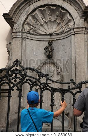 BRUSSELS, BELGIUM - AUGUST 13, 2012: Young boy looks at the Manneken Pis in Brussels, Belgium.