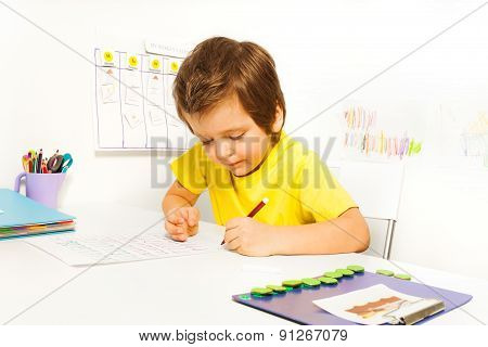 Concentrated small boy write with pencil alone