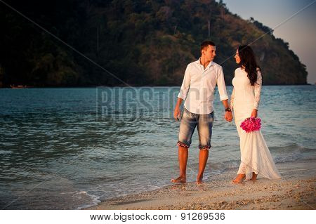 Bride And Groom Walk  At  Beach At Dawn