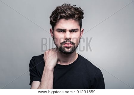 Young handsome man doubting on gray background