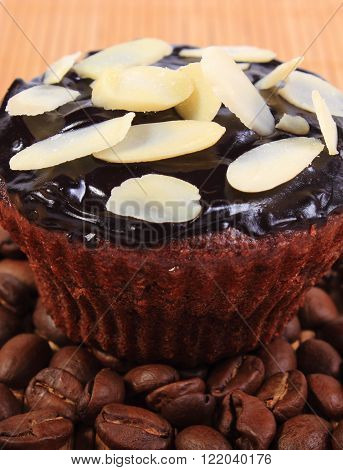 Homemade delicious fresh baked chocolate muffins with sliced almonds and coffee grains on wooden background concept for dessert