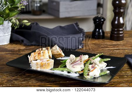 Stuffed turkey breast on the black plate snd wooden background. Chicken roulade