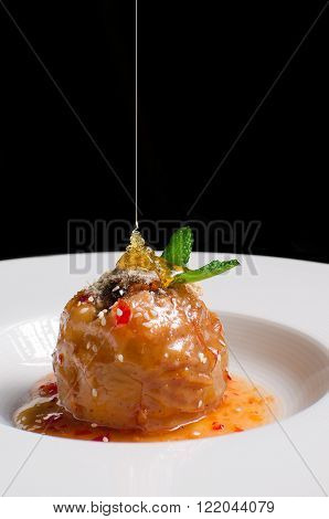 Baked apple with  honey caramel  on white ceramic plate on black background