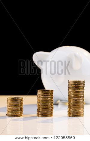 White piggy bank with a stack of coins and a black background