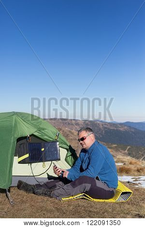 The man sitting next to mobile phone charges from the sun.