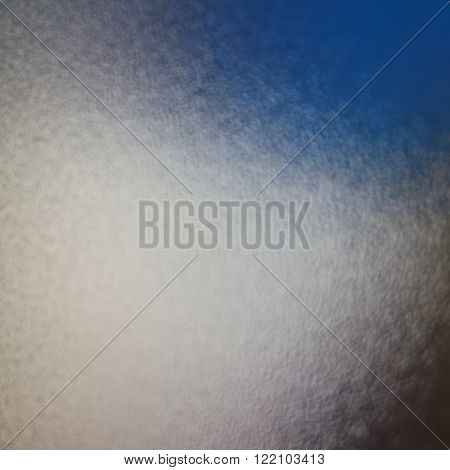Distorted and blurred blue sky through frosted glass with abstract effect in square format.