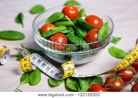 diet and weight loss concept - salad with spinach and tomatoes and measure tape on wooden table
** Note: Shallow depth of field