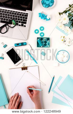 The female hands writing against blue fashion woman objects on white. Concept of female mockup
