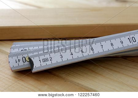 A white zollstock on a wood boards