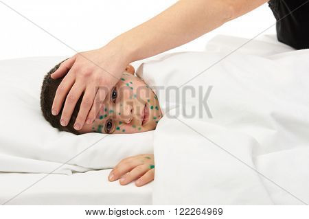 sick child has the virus on skin, mother's hand touches the forehead