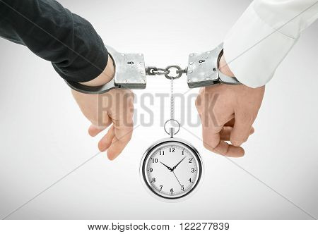Hands of two men fixed in handcuffs. Pocket wartch between them. Close up. Concept of accessory of crime.
