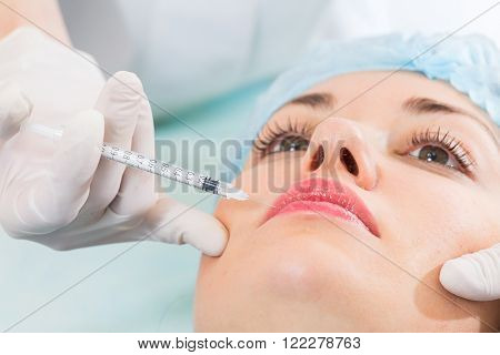 Subcutaneous injection into the girl's face. Doctor cosmetologist doing pull-injection in the face model. Syringe, face, needle, lift - the concept of rejuvenation. Tightening of the skin of the face.