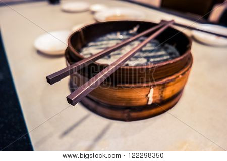 Traditional chinese food, steamed dumpling served on table in a wooden dish and with wooden chopsticks.
