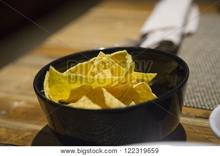 Nacho chips served in a black bowl