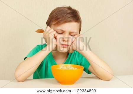 Little discontented boy does not want to eat a cereal