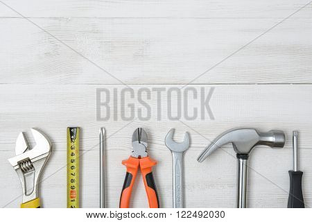 Top view of construction instruments and tools on wooden DIY workbench. Tape measure, wrench, hammer, pilers, screwdriver.