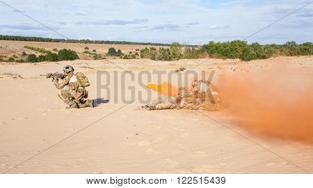 Squad of soldier evacuate the injured fellow in arms hiding in the smoke