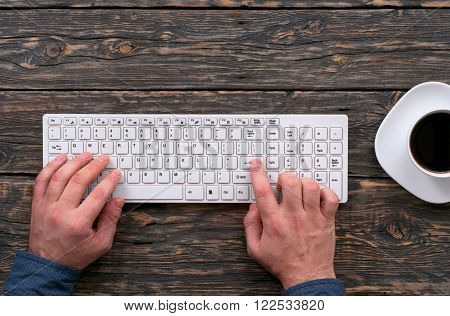 Man typing on a wireless computer keyboard. A man working at office desk. Top view