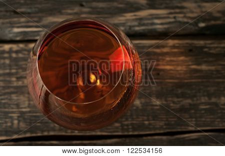 vintage cognac in large round glass on the old wooden background closeup. Top view with copy space