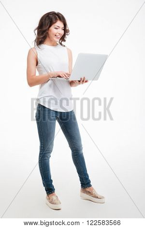 Full length portrait of a happy woman using laptop computer isolated on a white background
